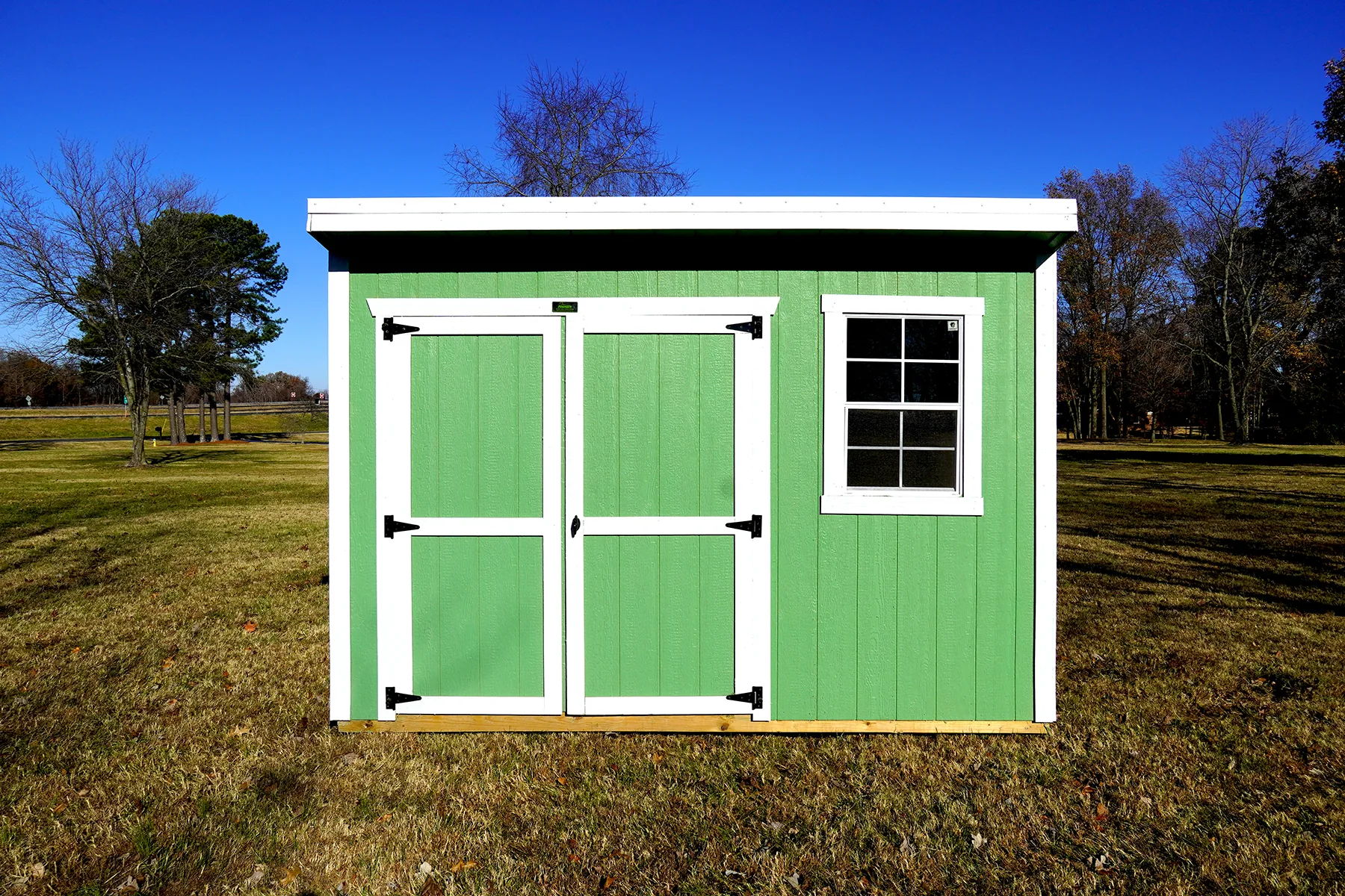 Green cottage shed shell with white double doors and a window